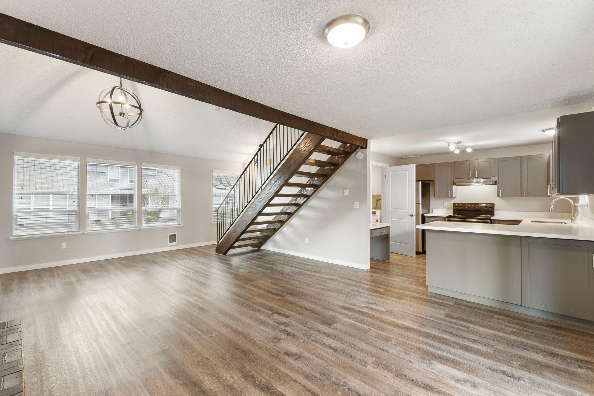 An empty living room with hardwood floors and a staircase leading to the second floor.