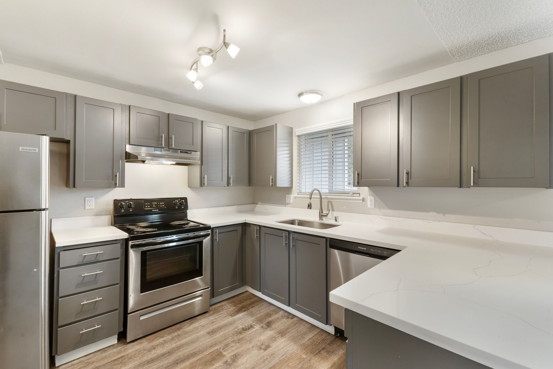 A kitchen with stainless steel appliances and gray cabinets.