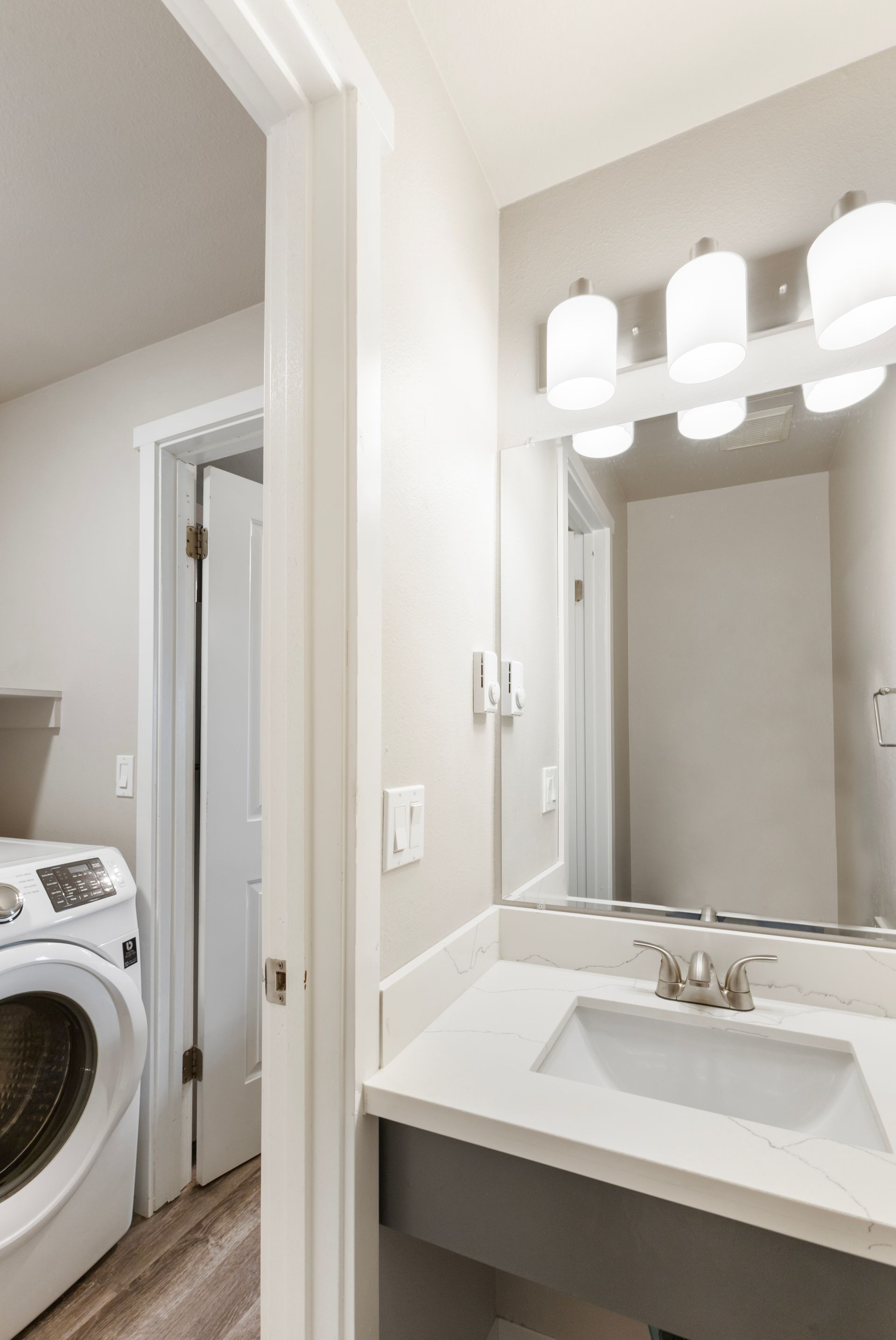 A bathroom with a sink , mirror and washer and dryer.