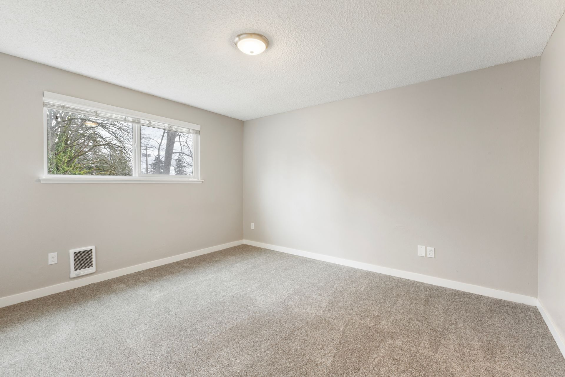 An empty room with a carpeted floor and a window.