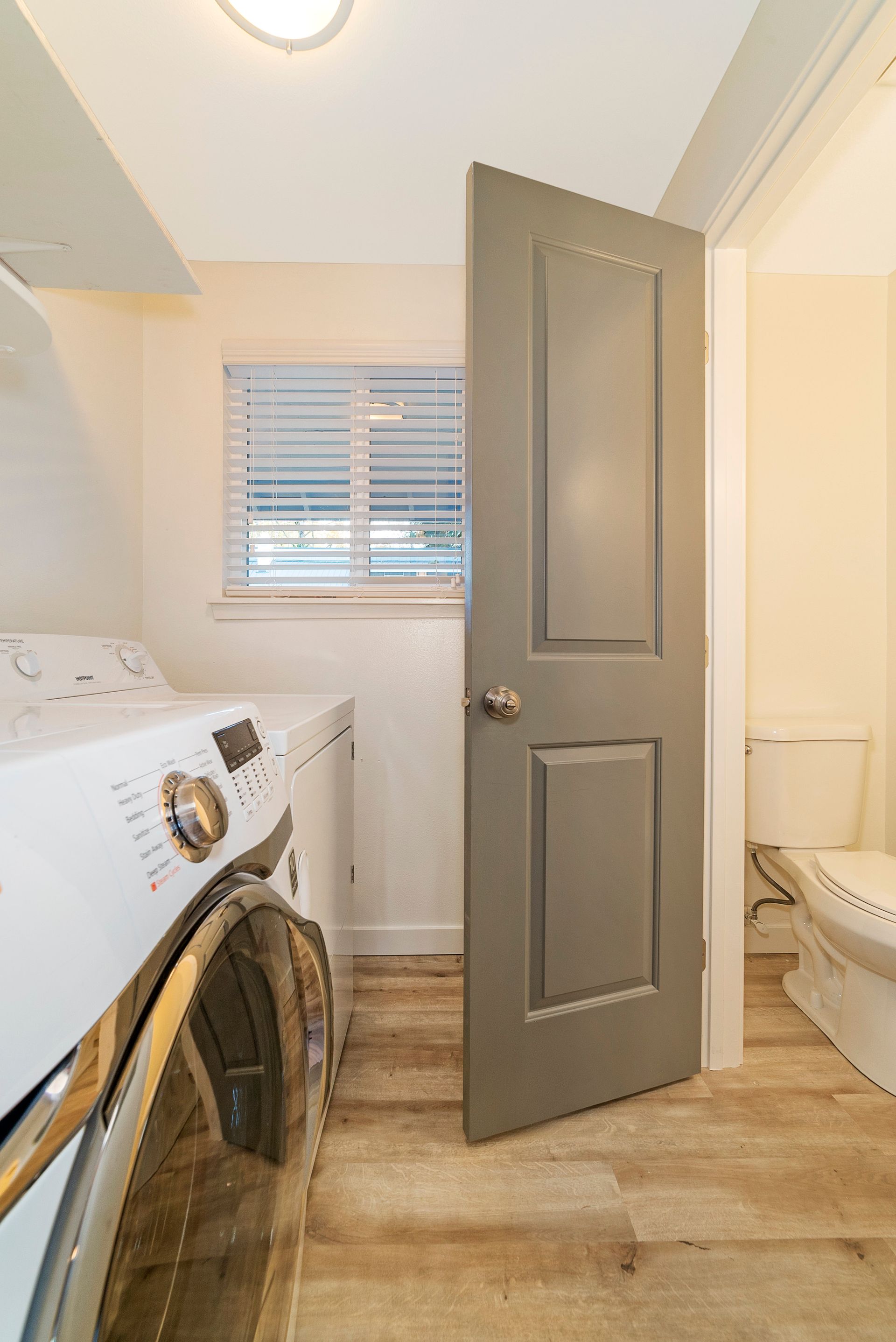 A laundry room with a washer and dryer and a toilet.