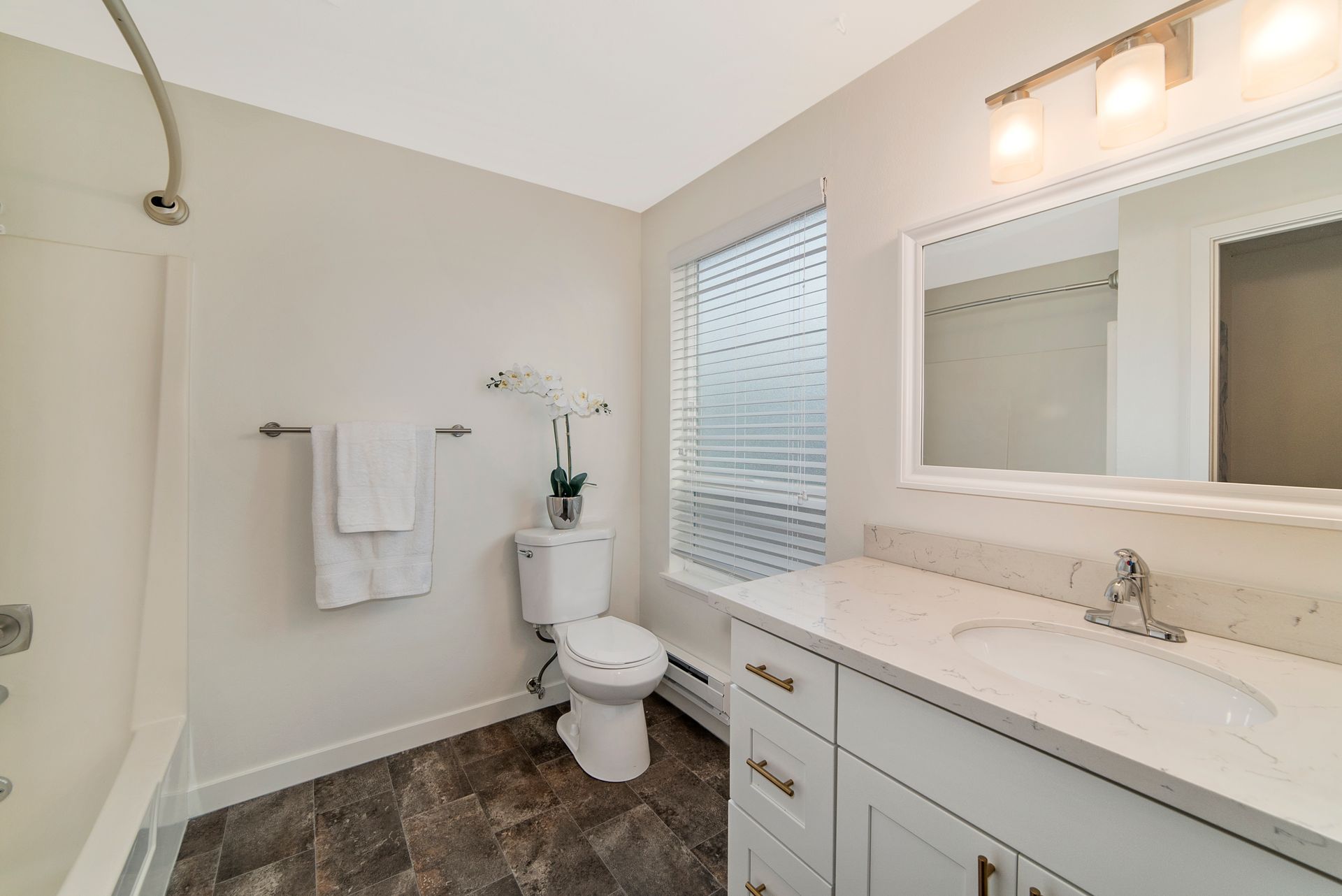 A bathroom with a toilet , sink , and mirror.