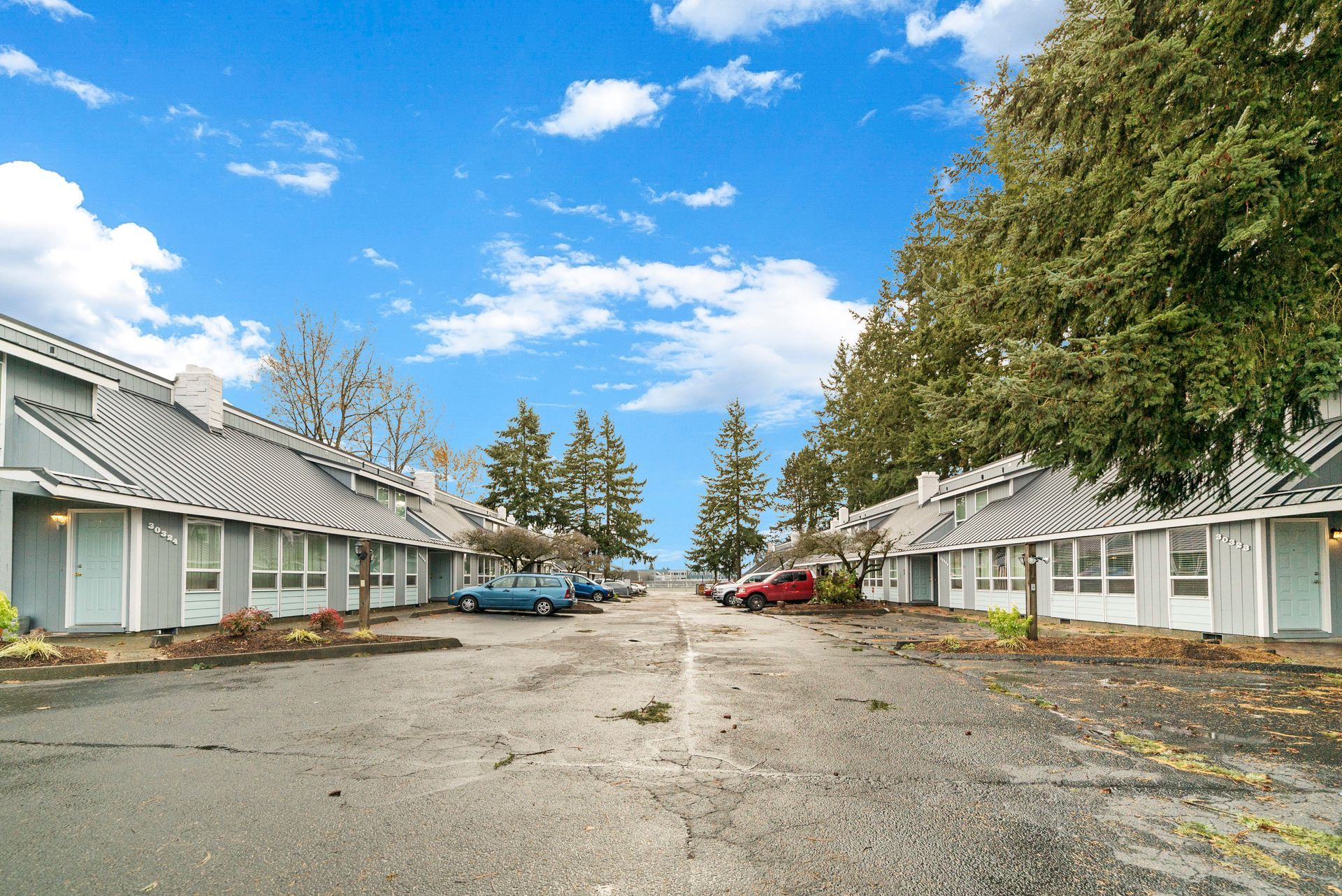 A row of motels with cars parked in front of them on a sunny day.