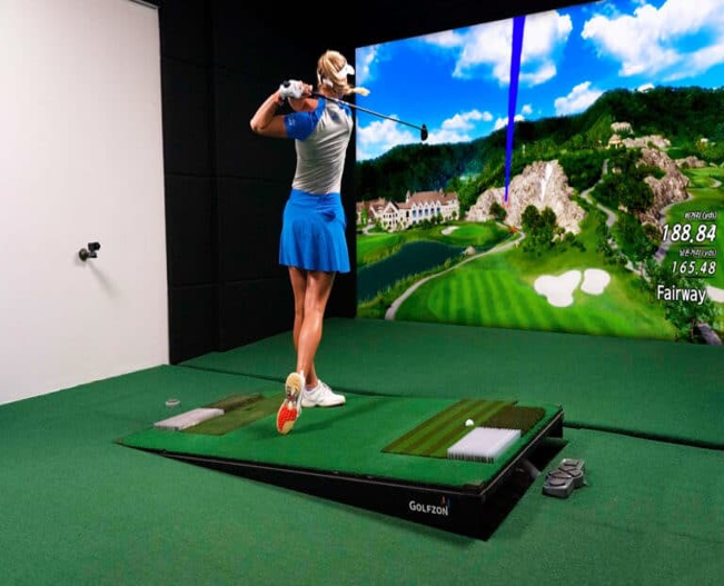 Golf instructor speaking to a small group beside a golf bag and course backdrop