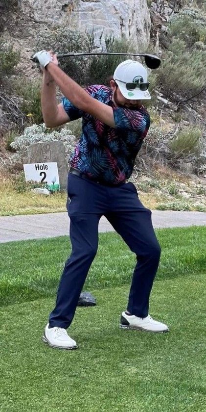 Golf ball on tee before a club on a green fairway at sunset