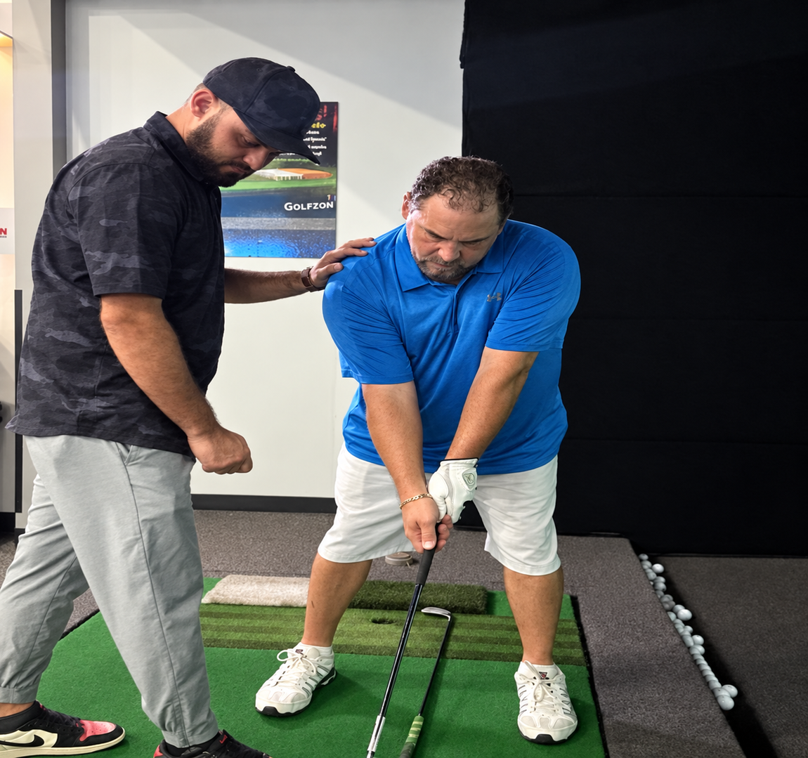 Golf instructor coaching a student on proper stance at an indoor golf simulator