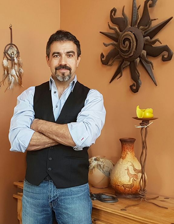 Man in black shirt holding coffee mug, smiling in a kitchen.