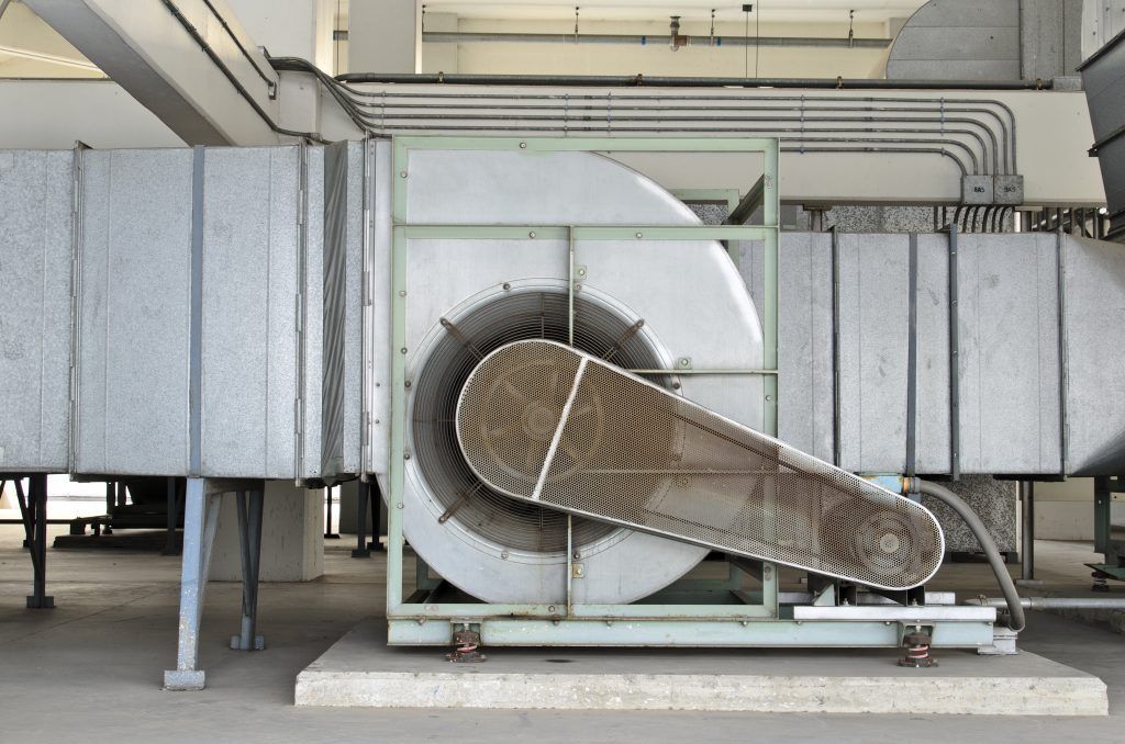 Un grand ventilateur est posé sur le sol dans un entrepôt.