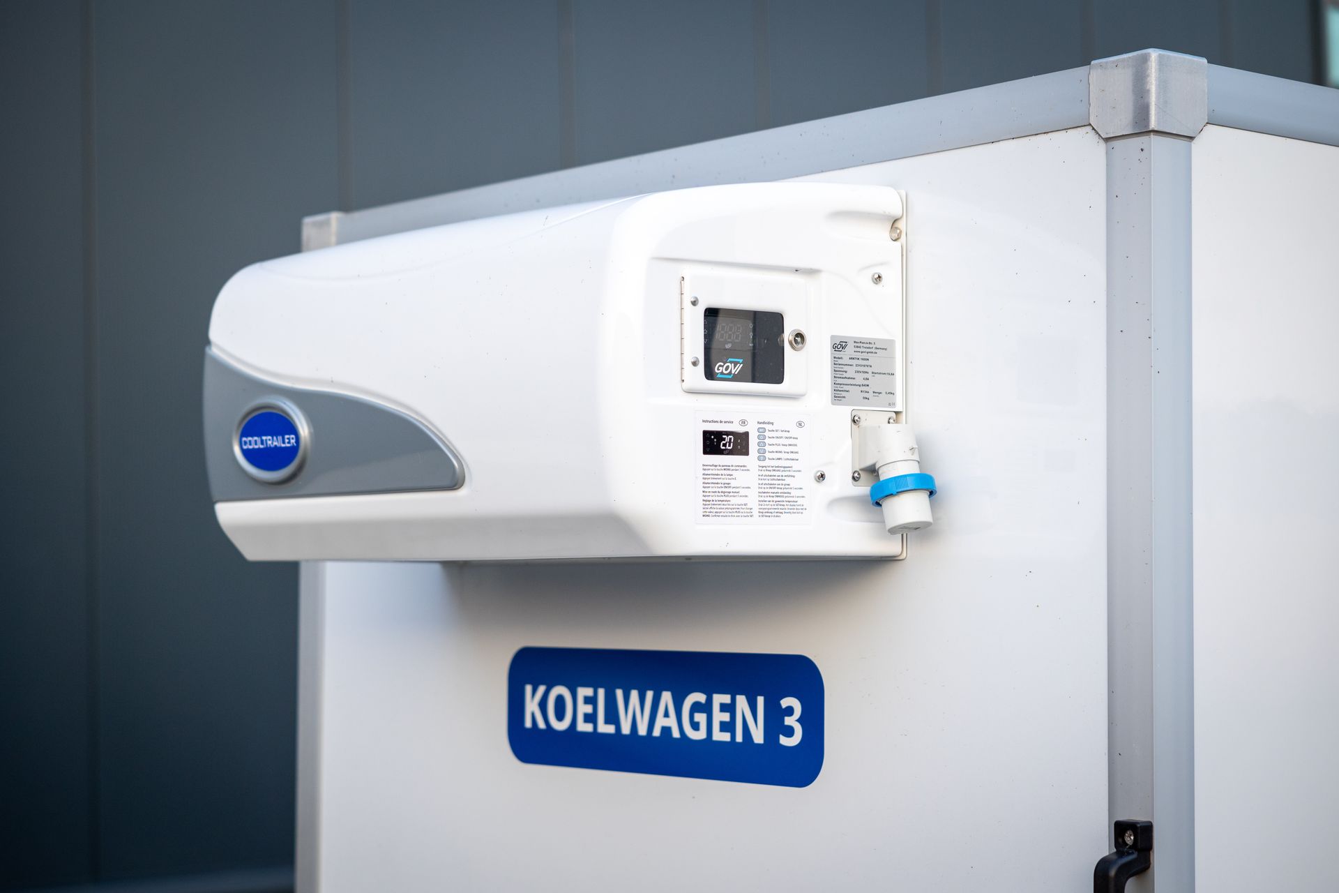 Een witte koelunit gemonteerd aan de zijkant van een koeltrailer met het opschrift 