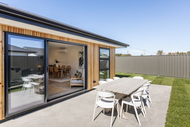 A patio with a table and chairs in front of a house.
