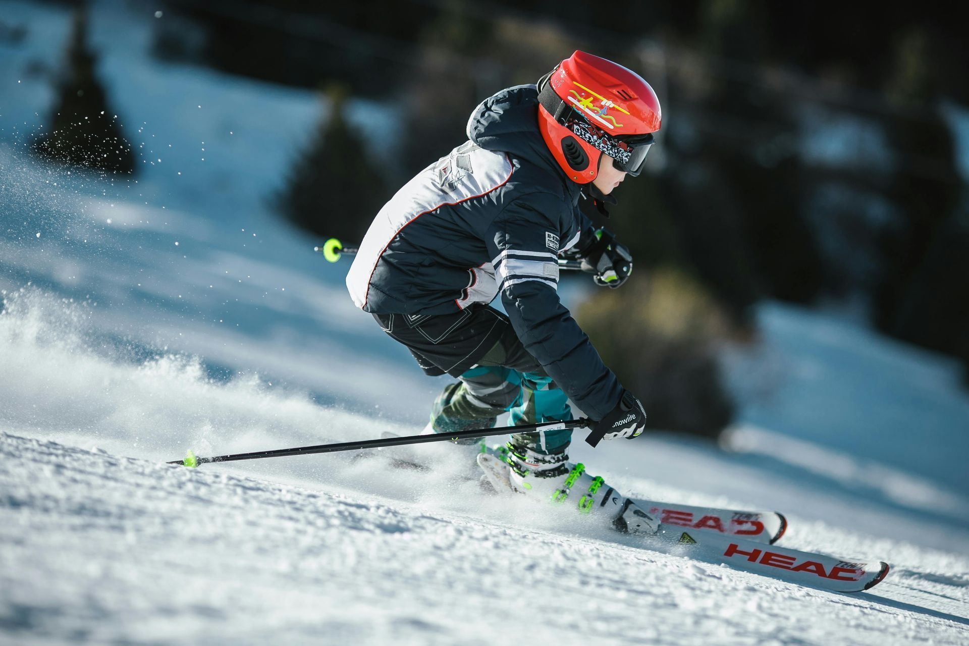 A young boy is skiing down a snow covered slope.