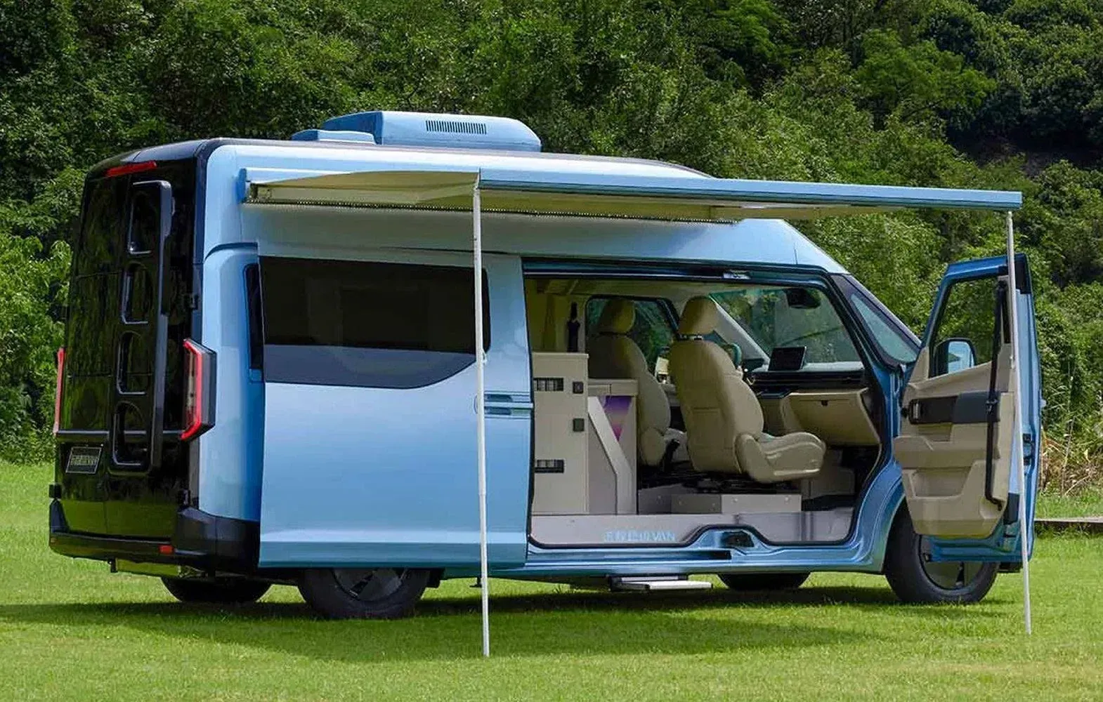 A light blue camper van parked on a grass field with its side doors open and an extended sun awning.