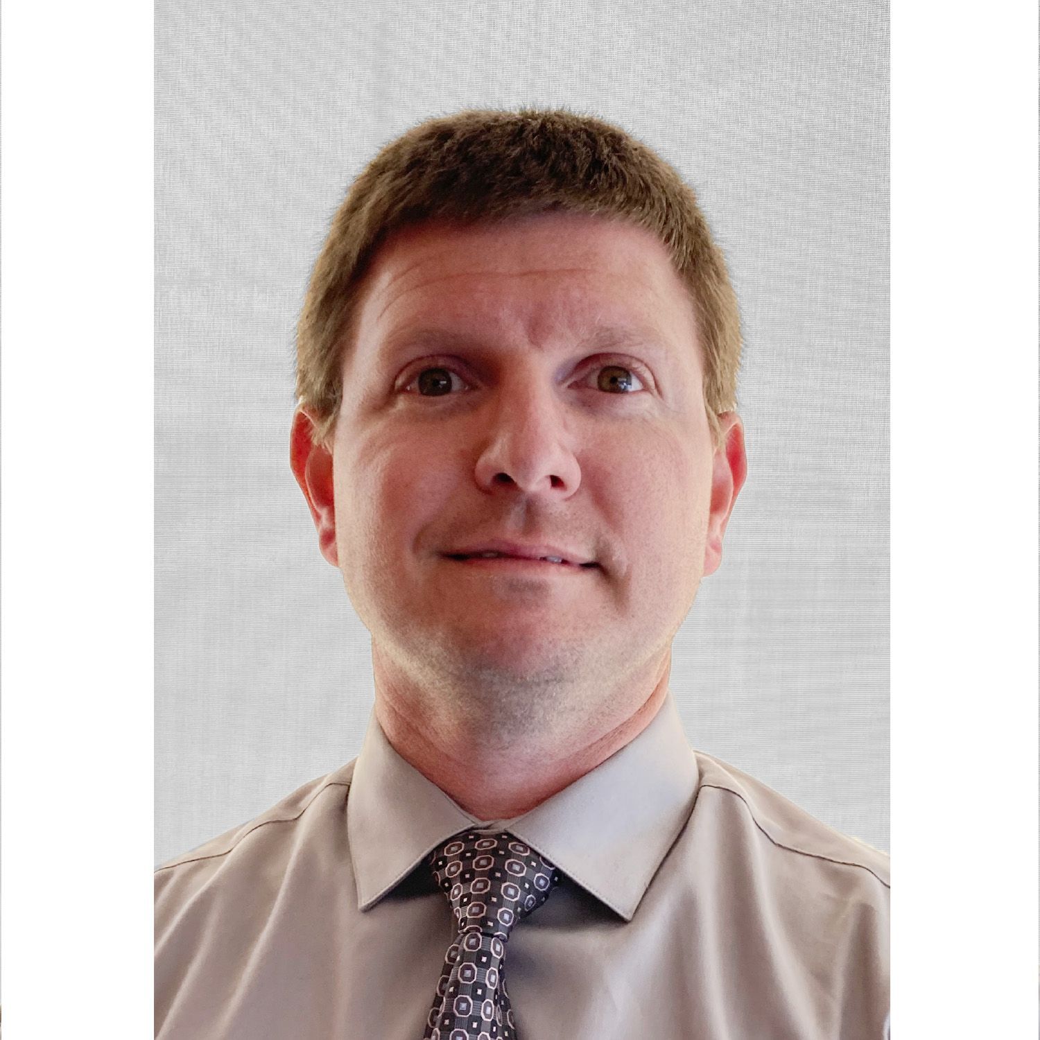 Portrait of a man in a light shirt and patterned tie against a plain white background
