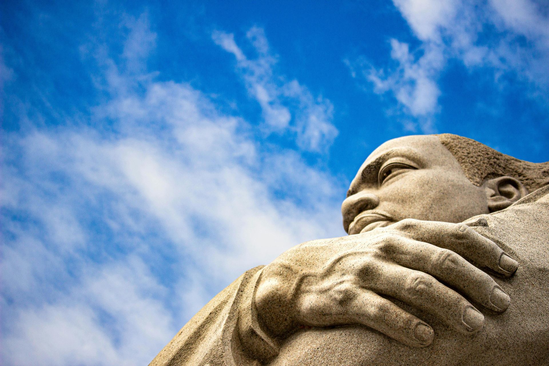 Close-up of a stone statue against a blue sky with clouds