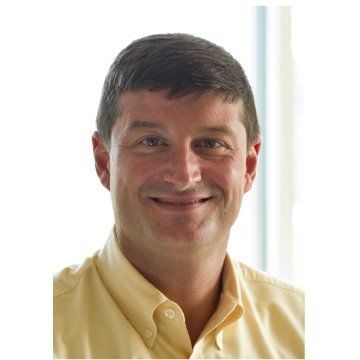 Smiling man in a yellow shirt against a bright white background