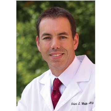 Smiling doctor in a white coat and red tie against a blurred green background