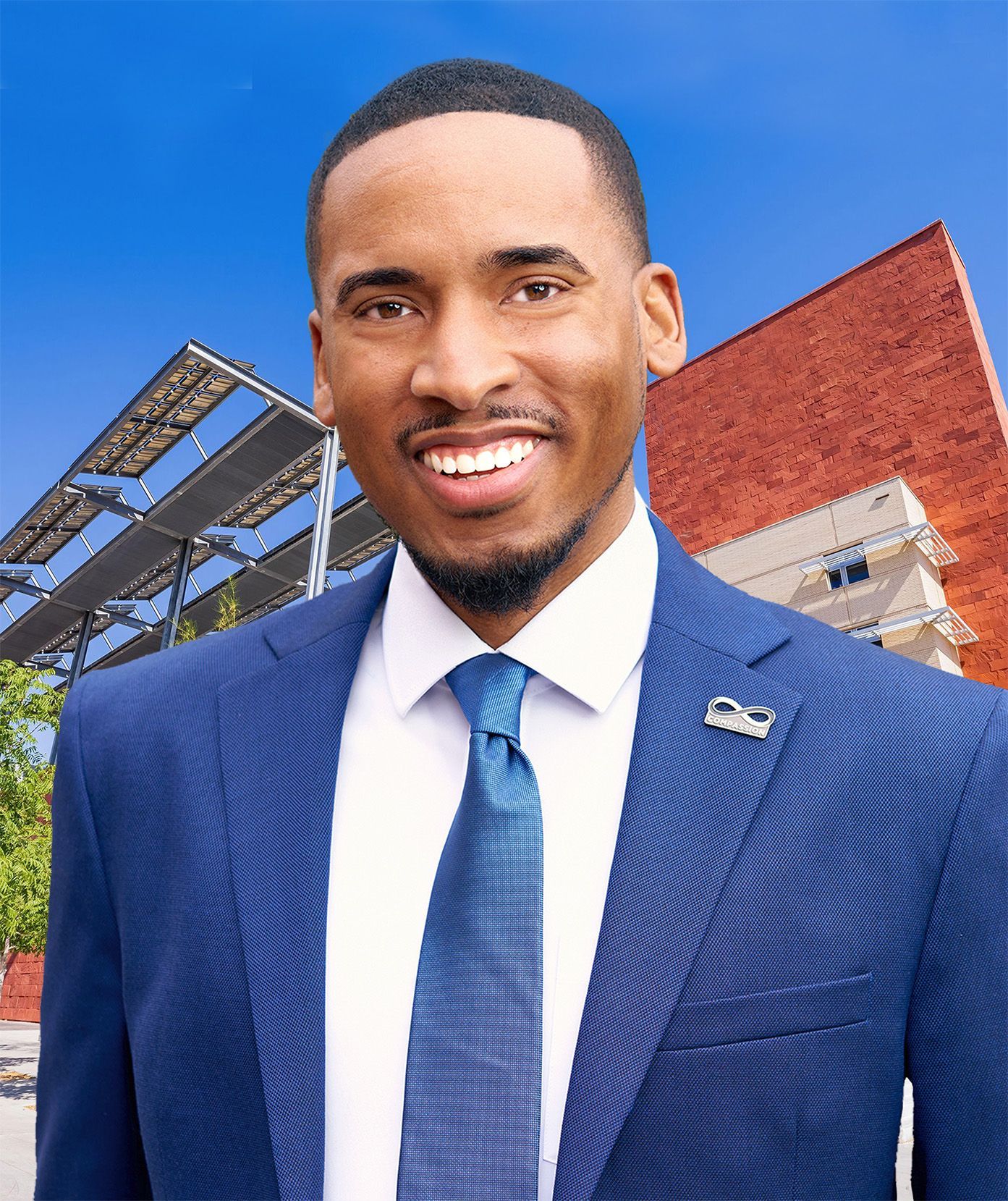 Smiling man in a blue suit and tie outdoors near a brick building under a clear blue sky