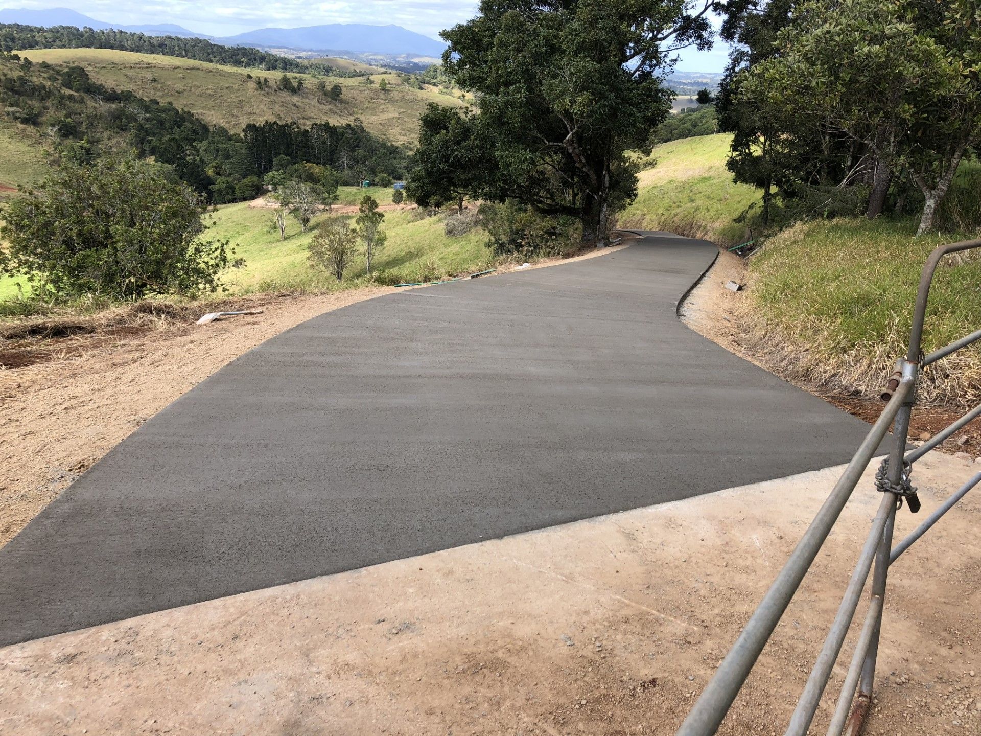 A Concrete Driveway Leads Down Through A Bush — Neil Stafford Concreting In Mareeba, QLD