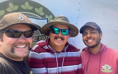 Three men wearing hats and sunglasses are posing for a picture.