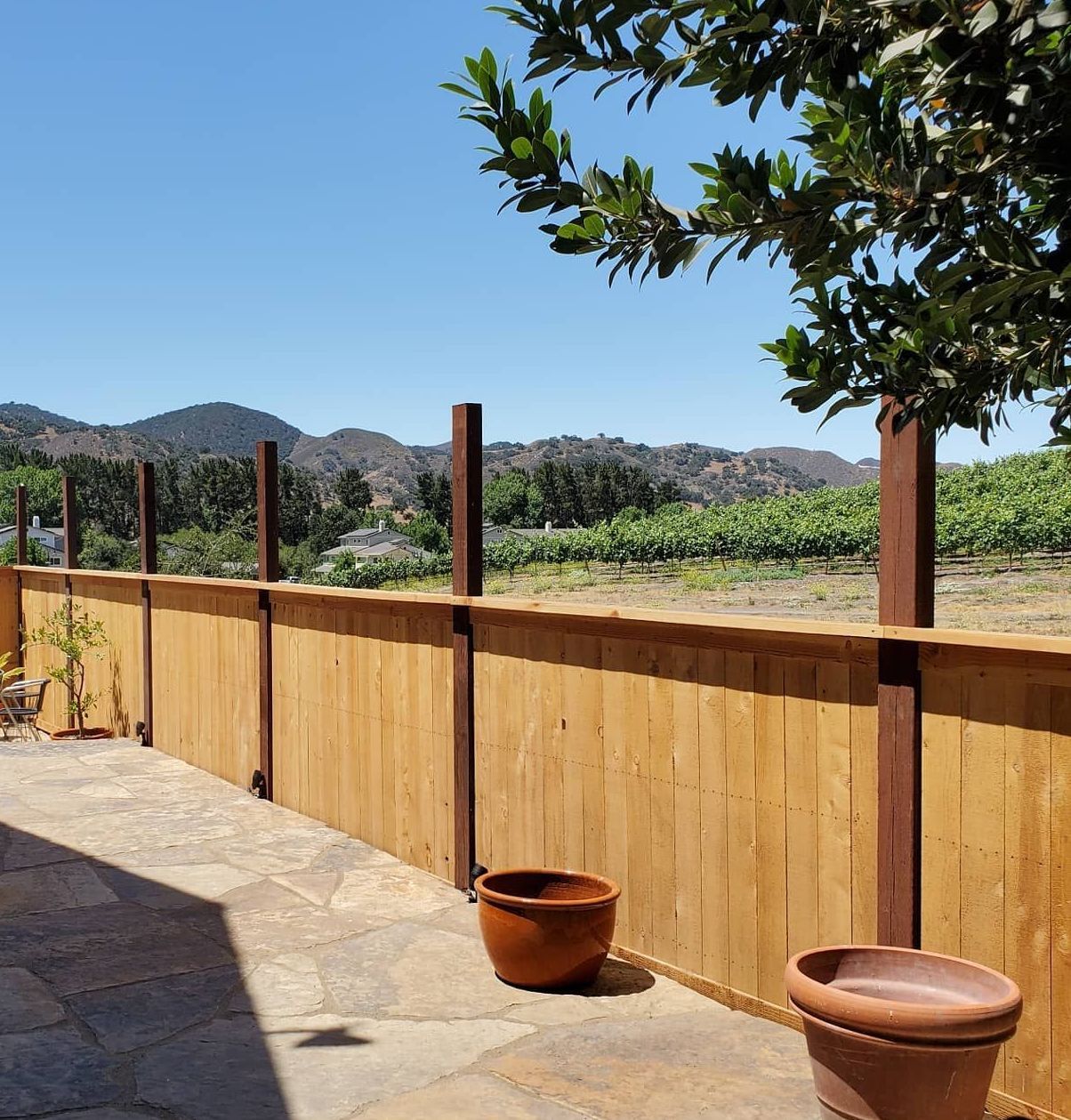 A wooden fence with a view of a vineyard