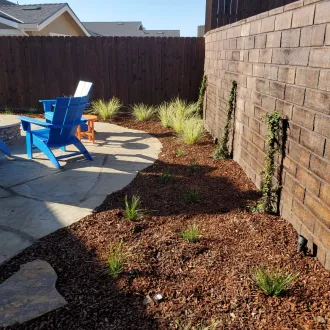 A blue chair sits on a patio next to a brick wall