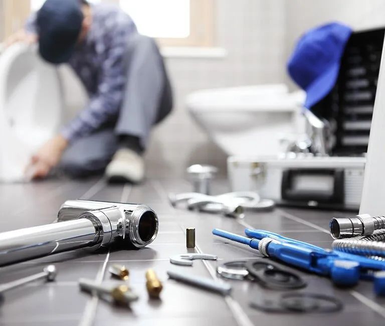 A Plumber Is Working On A Sink In A Bathroom — Andrew Logan Building In Gilgandra, NSW