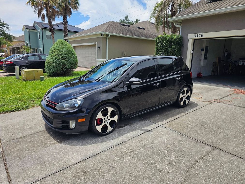 Black hatchback parked in a suburban driveway on a sunny day