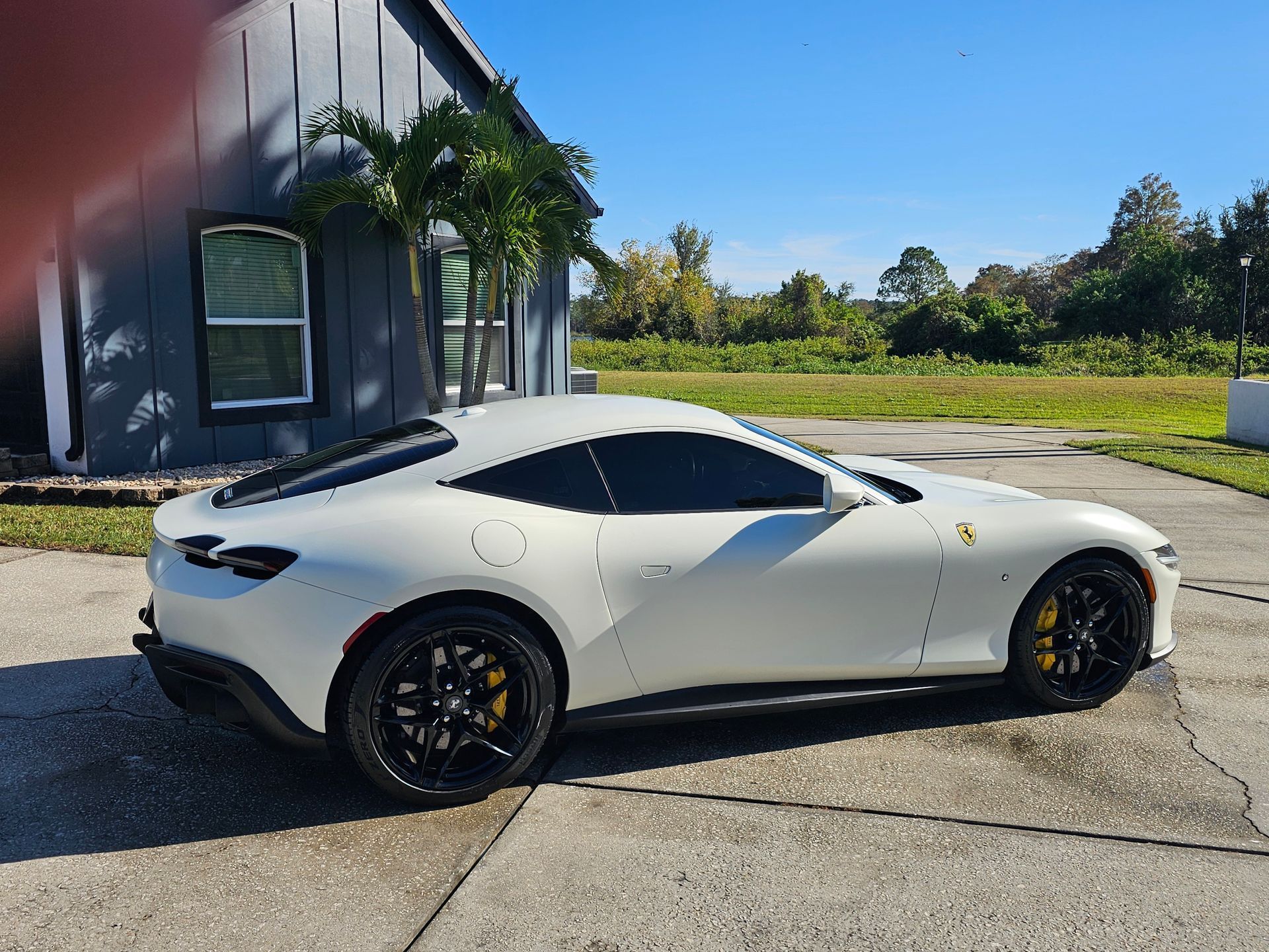 White Ferrari sports car parked beside a building on a sunny day