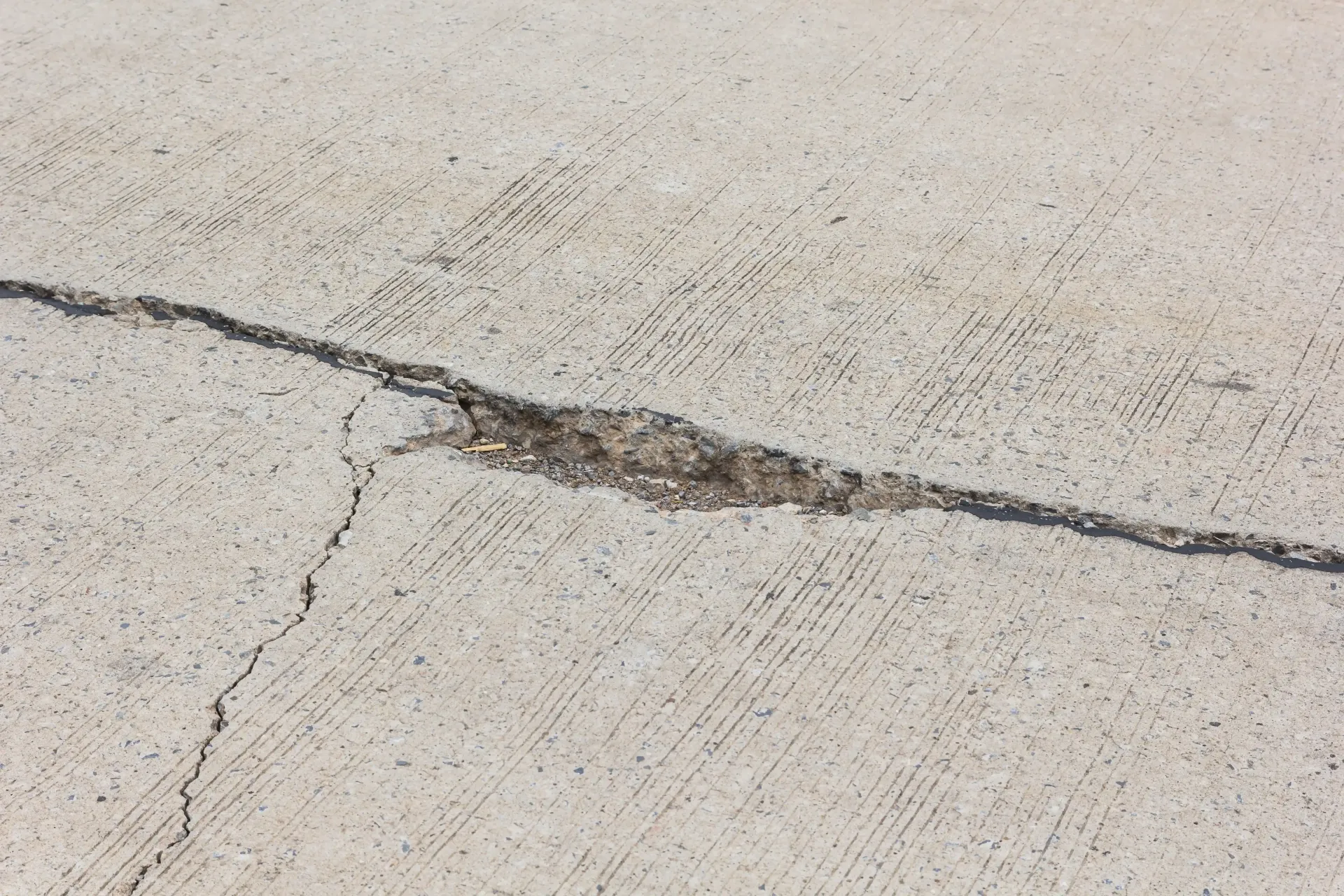 Cracked concrete pavement with a long dark fracture line