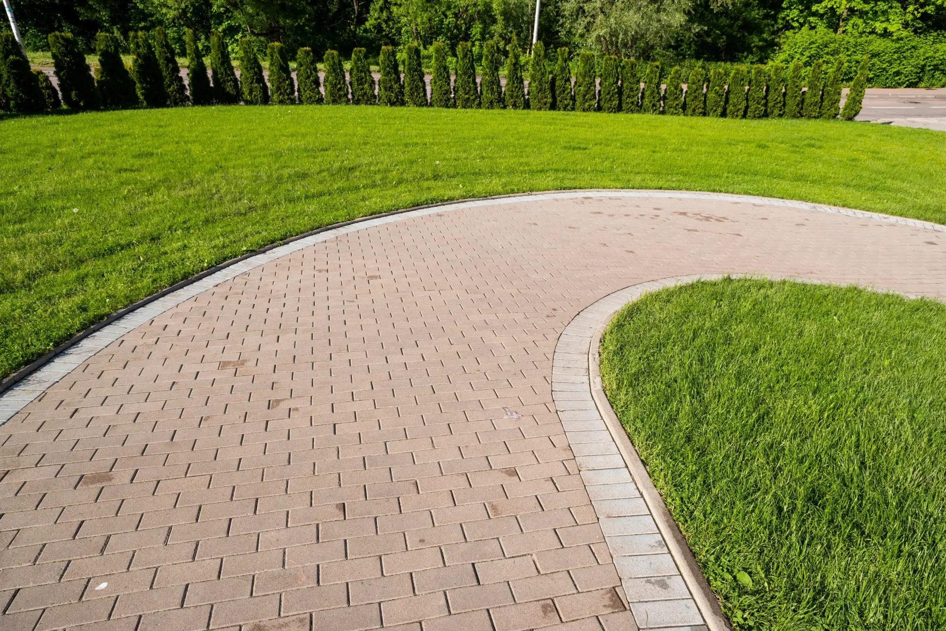 Concrete walkway winding through a yard with green grass on either side