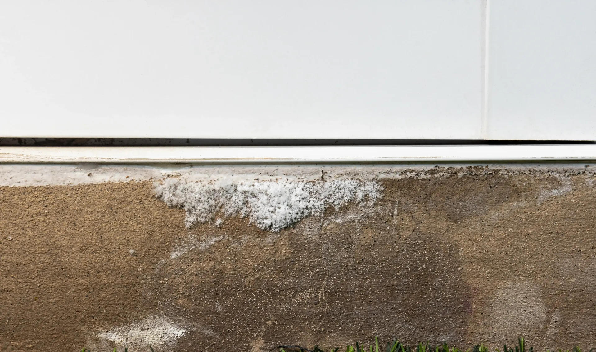 White and brown building exterior with water damage and white residue.