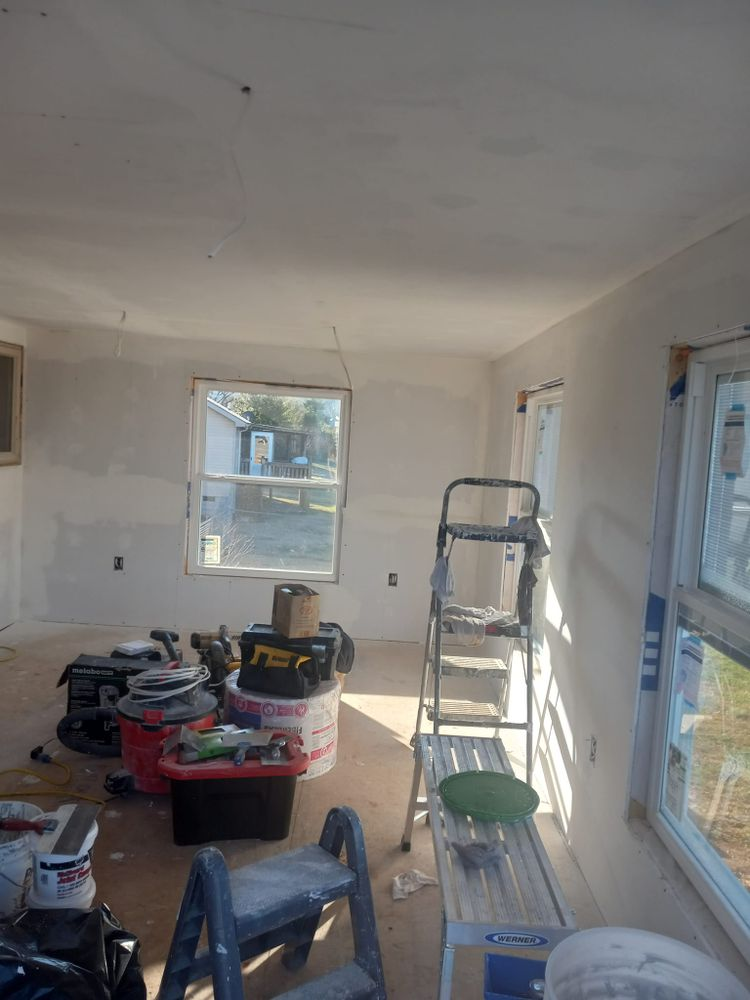 Interior room under construction with tools, ladders, and open windows; natural light.