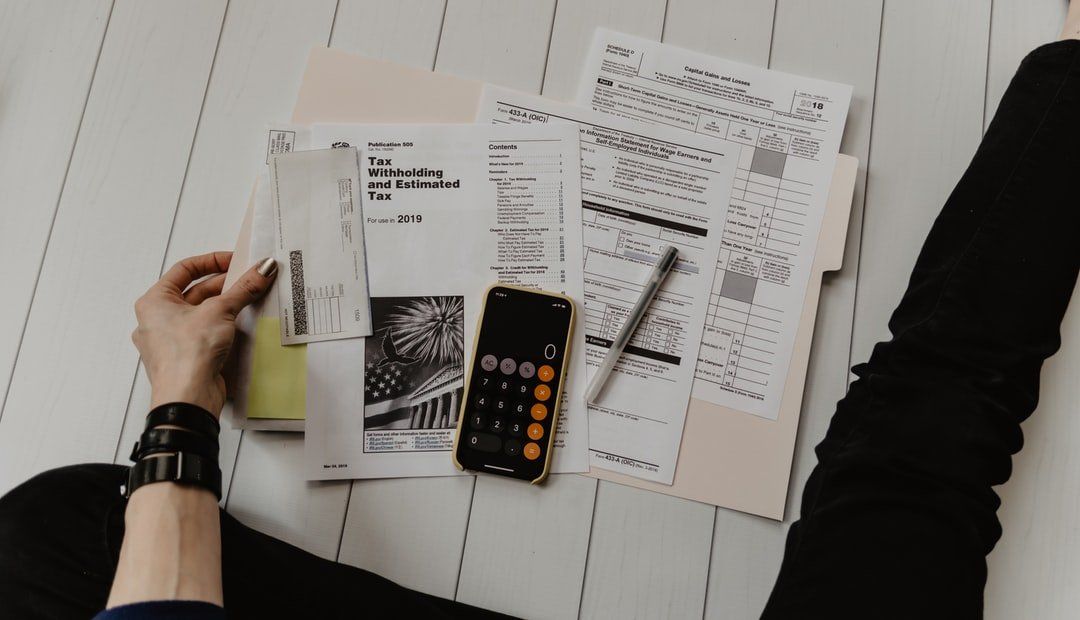 A person is working on paperwork with a calculator, representing the topic of tax preparation.