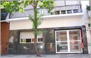 Un edificio con un balcón y un árbol delante.