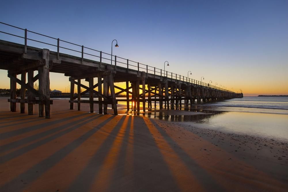 A Pier Leading Into The Ocean At Sunset — Torque Tech Supply & Repairs In Coffs Harbour, NSW