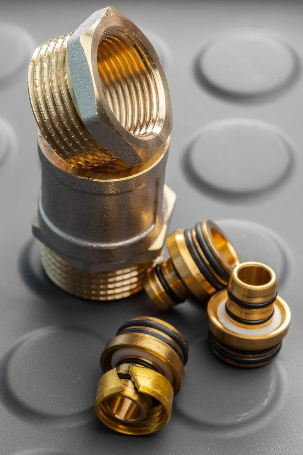 A Bunch Of Brass Fittings Are Stacked On Top Of Each Other On A Rubber Mat — Torque Tech Supply & Repairs In Port Macquarie, NSW