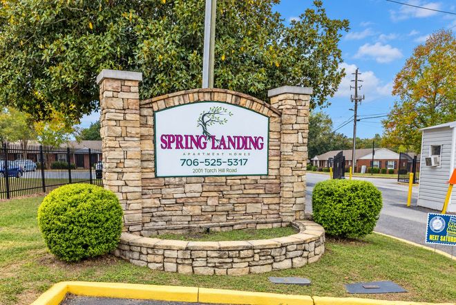 Spring Landing sign on stone monument, surrounded by shrubs and trees outdoors