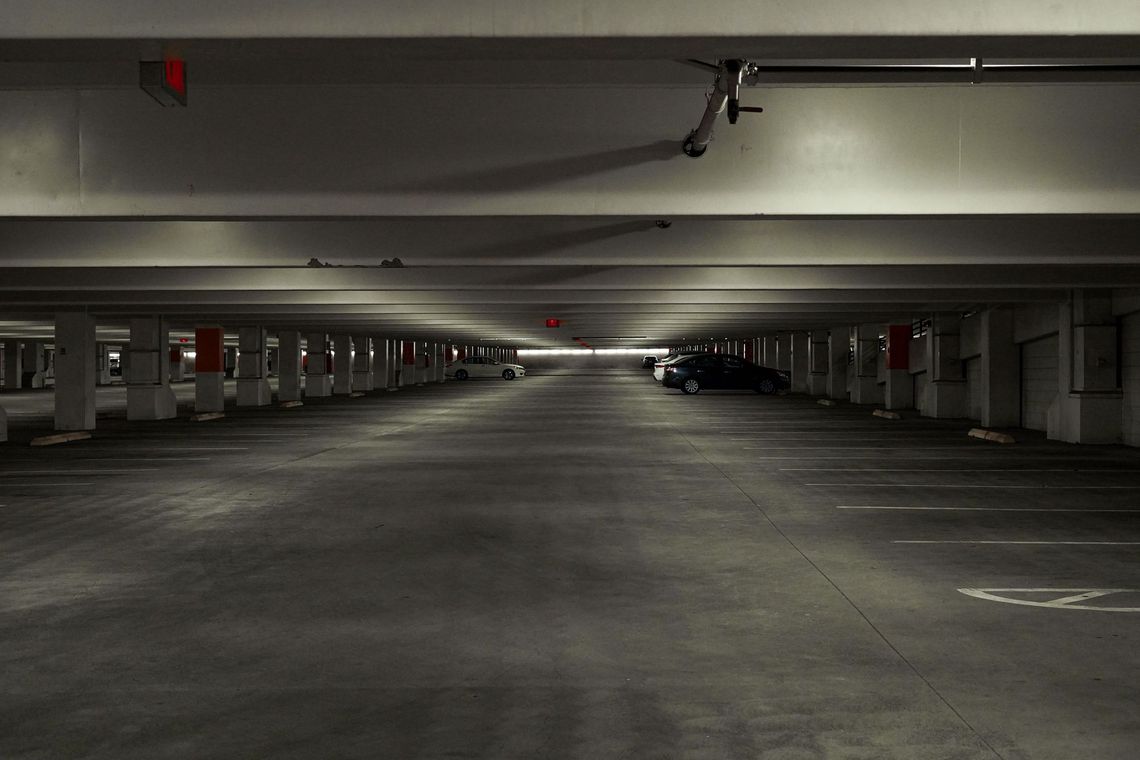 Garage sotterraneo vuoto con file di pilastri in cemento e una fioca illuminazione dall’alto