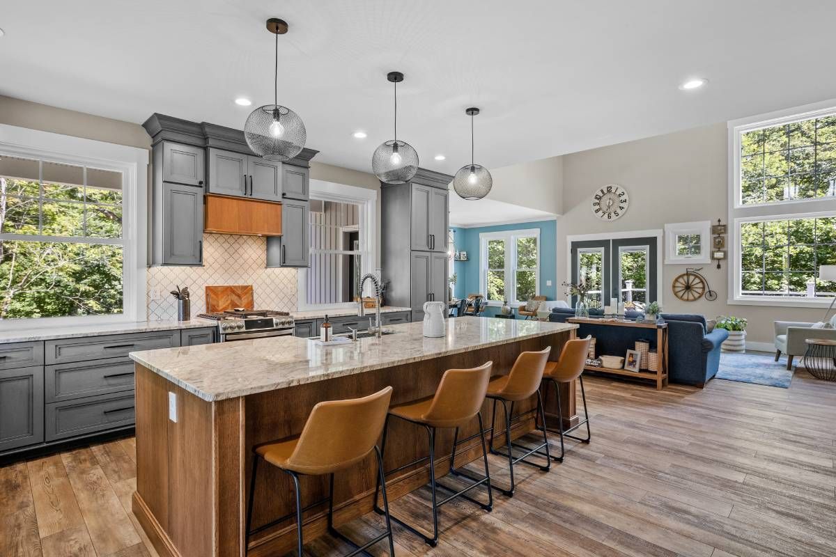 A modern kitchen and living room space with lots of windows at Schön Interiors near Braunfels, Texas
