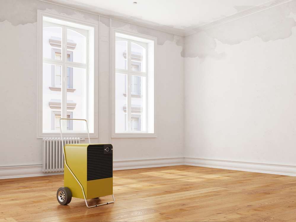 An empty room with a yellow air conditioner on the floor.