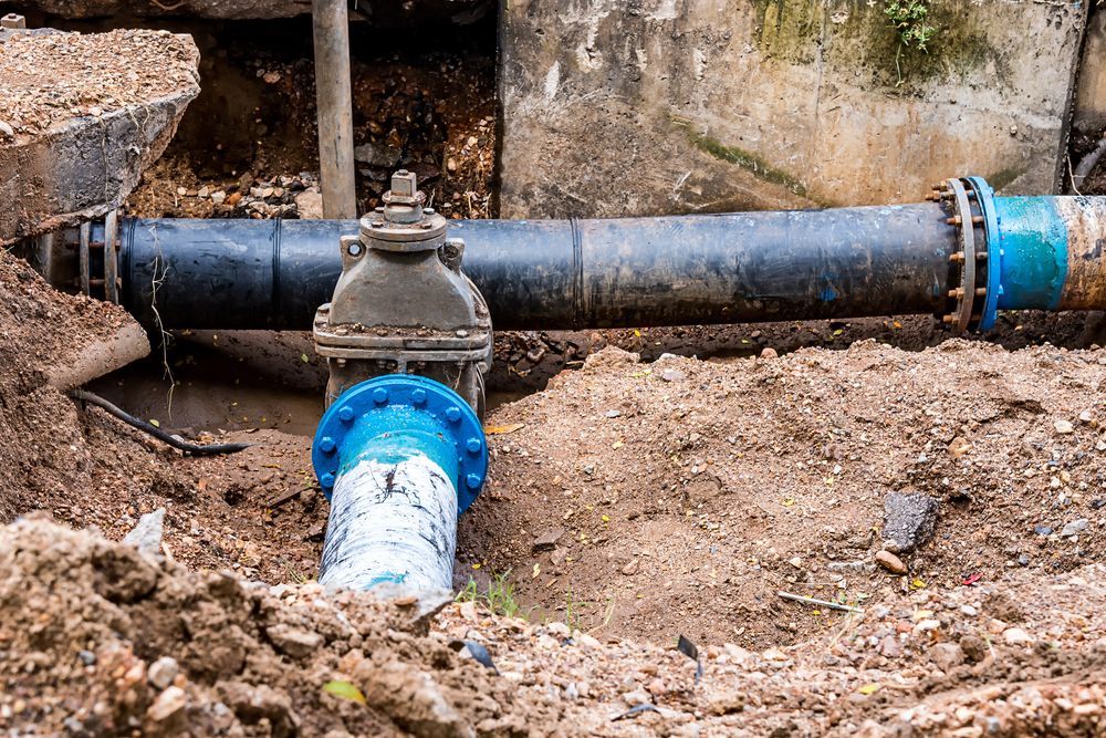 A Water Pipe is Sitting in the Dirt Next to a Wall — Puzzles Plumbing & Excavations in Lismore, NSW