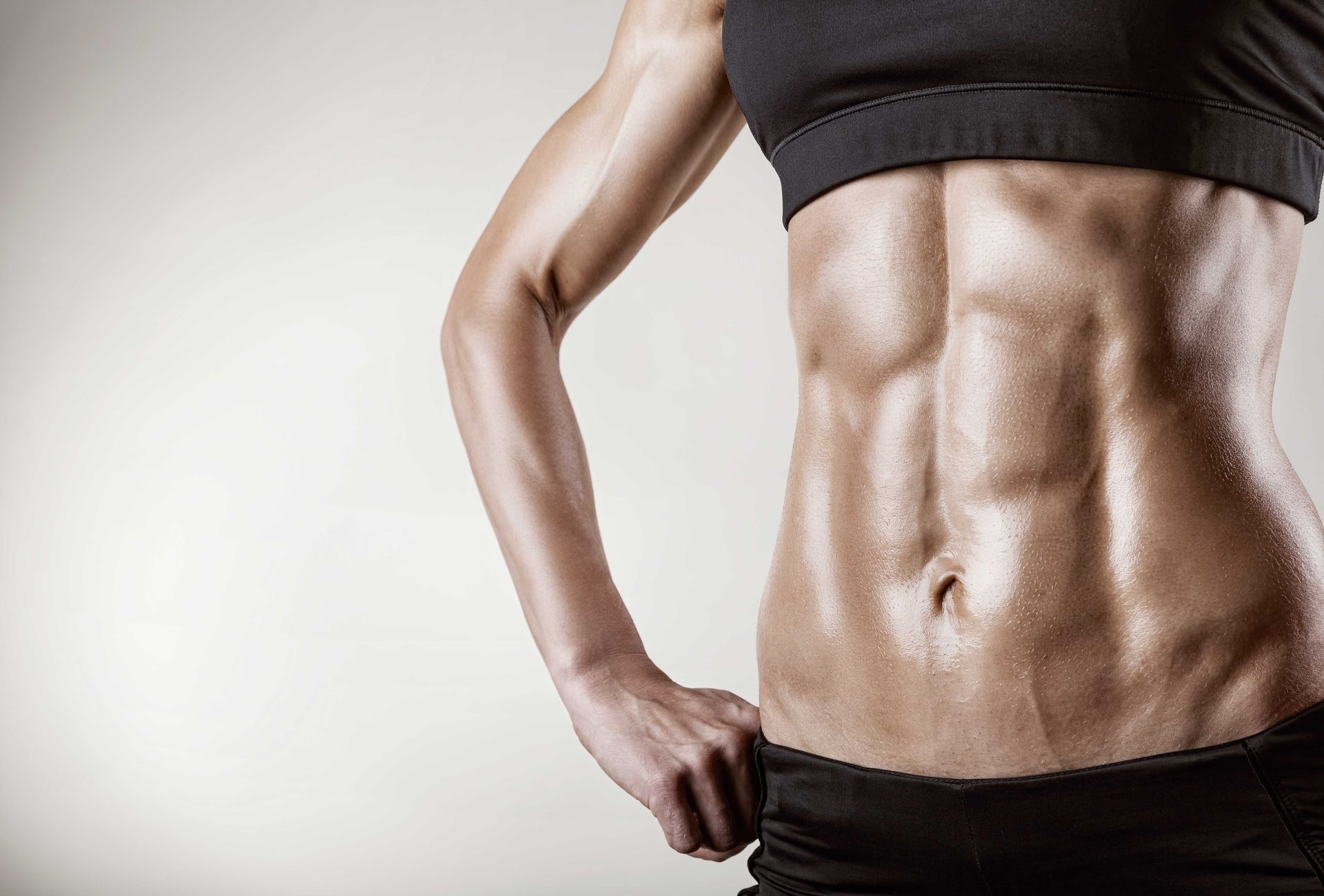 A woman with a muscular stomach is standing with her hands on her hips
