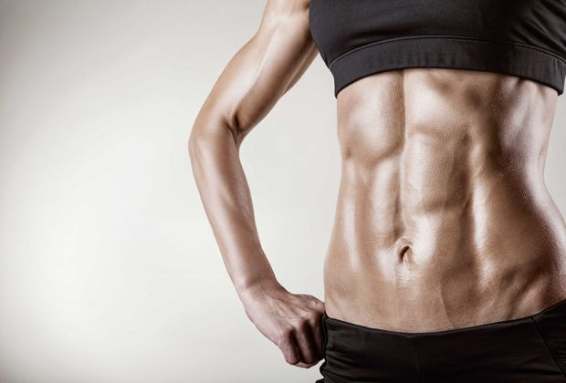 A woman with a muscular stomach is standing with her hands on her hips