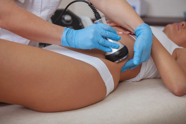 A woman is getting a cavitation treatment on her stomach