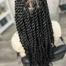A woman is sitting in a chair with her hair in braids