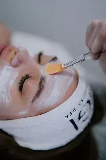 A woman is getting a facial treatment with a brush on her face