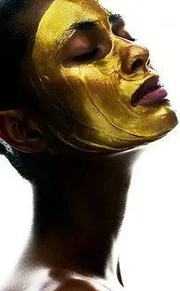 A woman is wearing a gold mask on her face