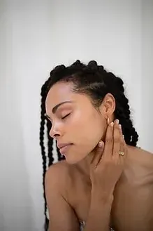 A woman with braids is touching her ear with her hand