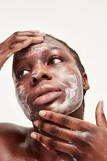 A woman is applying a facial mask to her face
