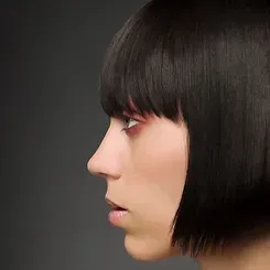 A close up of a woman 's face with short black hair and bangs